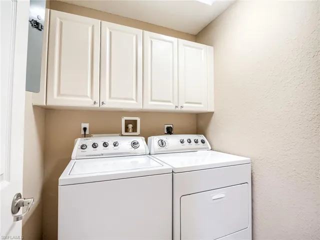 Washroom featuring washing machine and dryer and cabinets