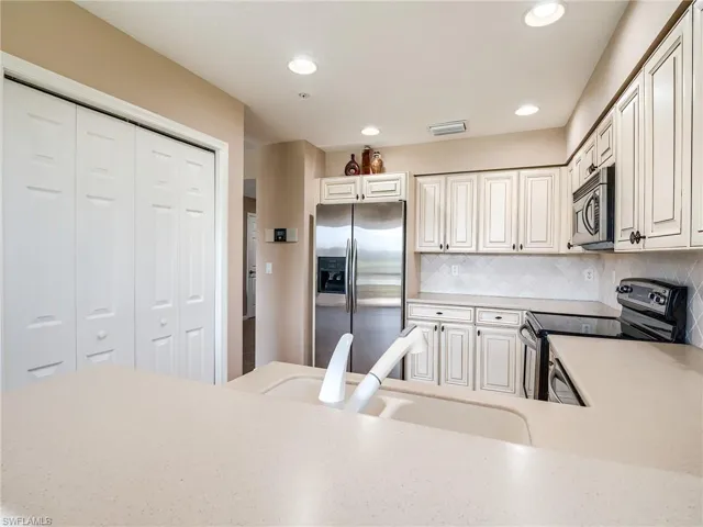 Kitchen featuring white cabinetry, sink, stainless steel appliances, and tasteful backsplash