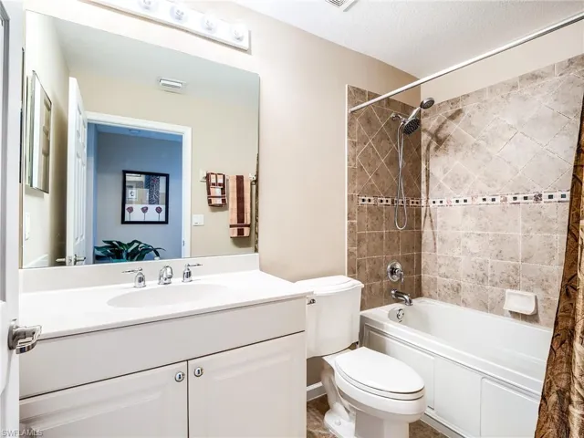 Full bathroom with toilet, tile patterned flooring, vanity, a textured ceiling, and shower / bathtub combination with curtain