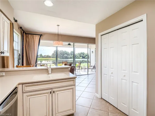 Kitchen featuring sink, decorative light fixtures, dishwashing machine, light tile patterned floors, and cream cabinetry