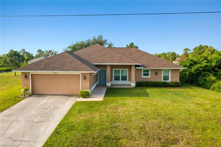 Ranch-style home featuring a garage and a front lawn