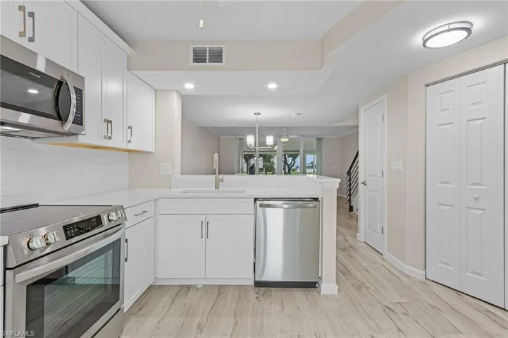 Kitchen featuring decorative backsplash, white cabinets, appliances with stainless steel finishes, sink, and kitchen peninsula