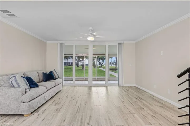 Living room featuring ceiling fan, light wood-type flooring, and ornamental molding