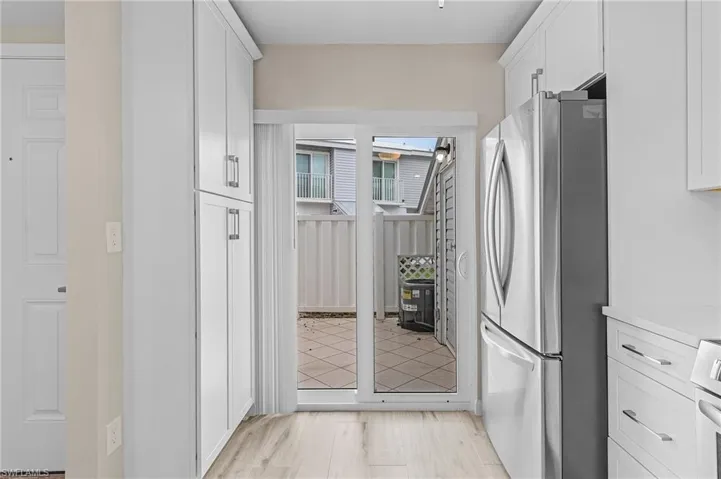 Kitchen featuring white cabinets, light hardwood / wood-style flooring, and stainless steel fridge