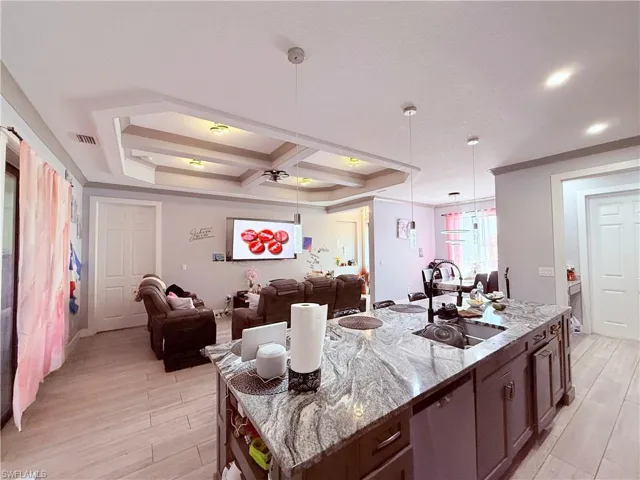Open concept living space featuring a kitchen island with granite countertops, an undermount sink, and dark wood cabinetry