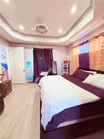 Recessed lighting illuminates the tray ceiling, complementing the wood-finish flooring