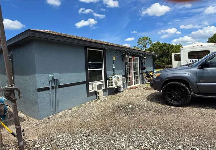 Stucco exterior with a dark trim, featuring a sliding glass door entry and multiple windows