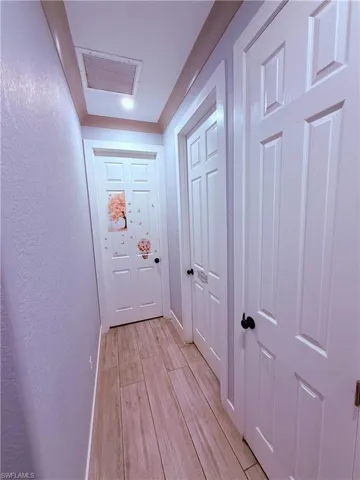 Hallway featuring wood-finish flooring, white paneled doors, and recessed lighting
