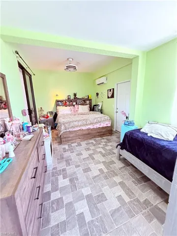 Spacious room featuring patterned tile flooring, a built-in wall air conditioning unit, and a ceiling fan