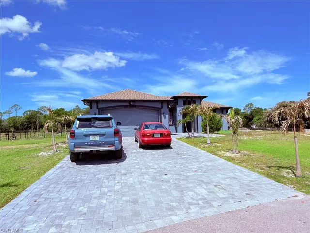 Contemporary exterior with a tiled roof, paver driveway, and an integrated two-car garage