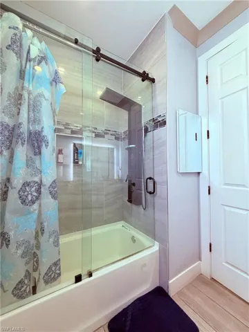 Shower-over-tub combination with clear glass sliding doors and matte black hardware