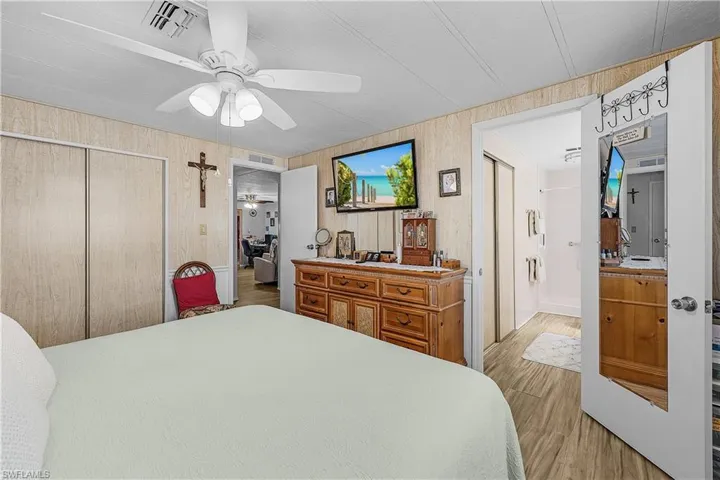 Bedroom with visible vents, a closet, ceiling fan, wood finished floors, and wood walls