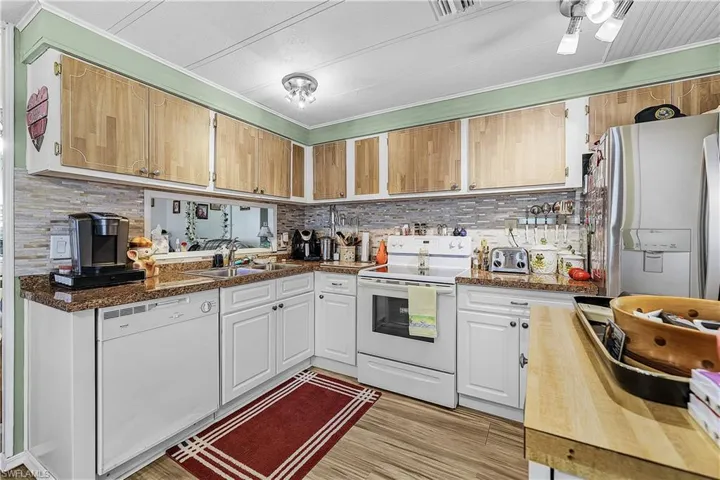 Kitchen featuring backsplash, ornamental molding, a sink, and white appliances