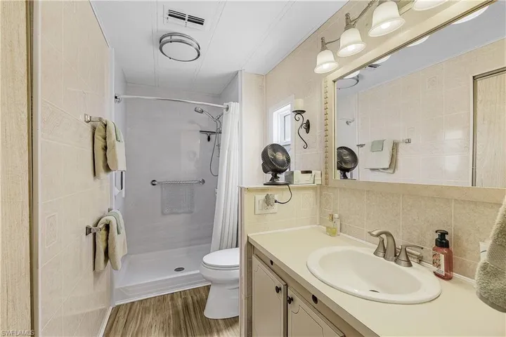 Bathroom with toilet, tile walls, vanity, backsplash, and a stall shower