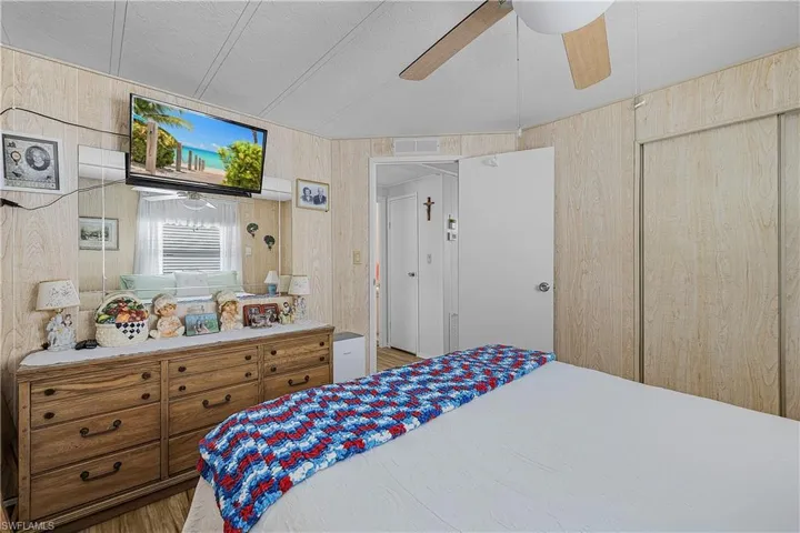 Bedroom featuring wooden walls, visible vents, ceiling fan, and wood finished floors