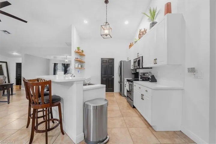 Kitchen with white cabinetry, appliances with stainless steel finishes, a breakfast bar area, and light tile patterned floors