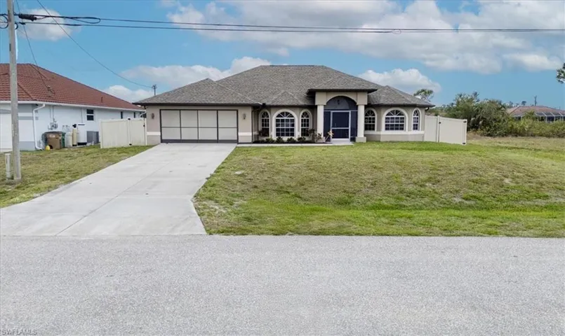 French country inspired facade with an attached garage, concrete driveway, a front lawn, and stucco siding
