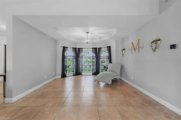 Sitting room featuring baseboards, a tray ceiling, a chandelier, and light tile patterned floors