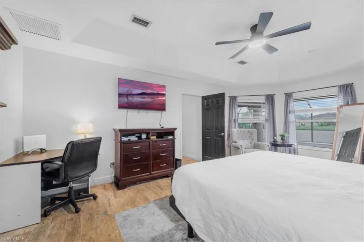 Bedroom featuring baseboards, wood finished floors, visible vents, and a raised ceiling