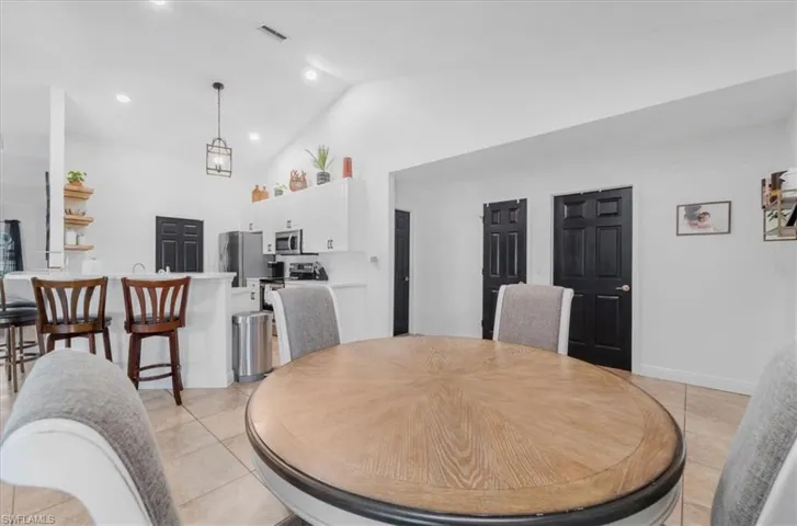 Dining room featuring light tile patterned flooring, baseboards, visible vents, recessed lighting, and high vaulted ceiling