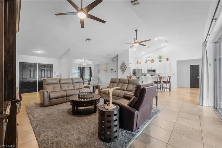 Living area featuring a ceiling fan, visible vents, high vaulted ceiling, and light tile patterned floors