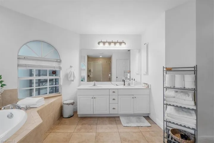 Bathroom featuring a bath, double vanity, a stall shower, and a sink