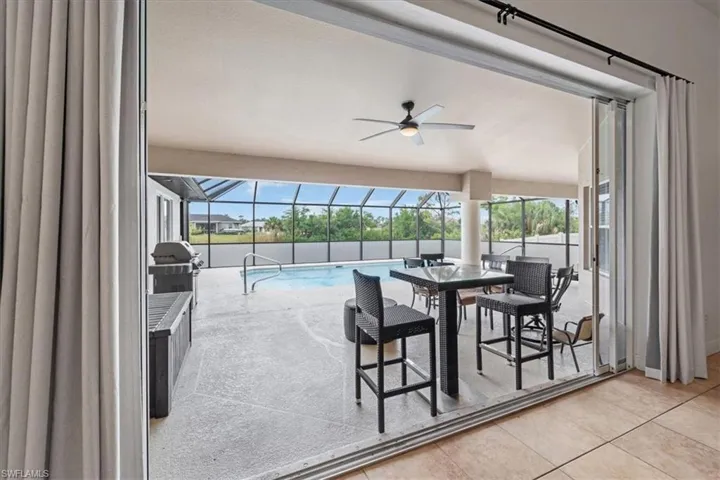 View of swimming pool featuring a ceiling fan, a fenced in pool, glass enclosure, and a patio area