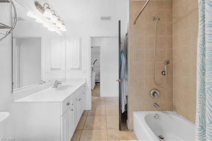 Bathroom with vanity, tile patterned flooring, shower / tub combo with curtain, and visible vents