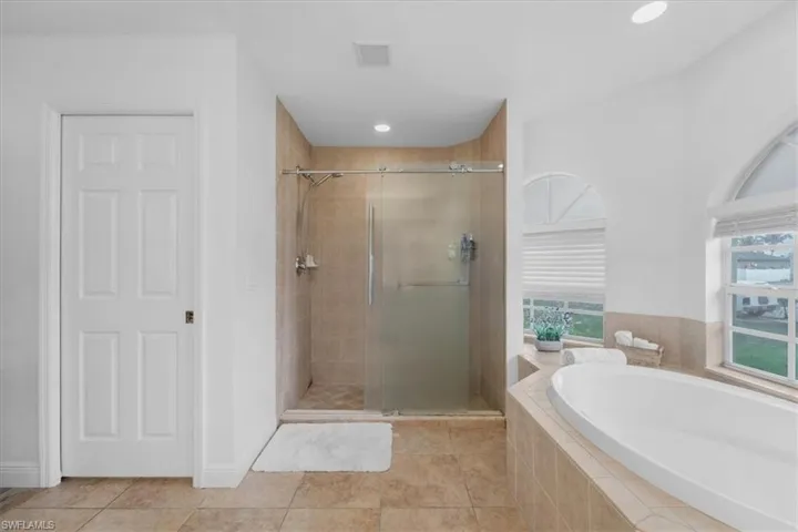 Full bath with a bath, a healthy amount of sunlight, a stall shower, and visible vents