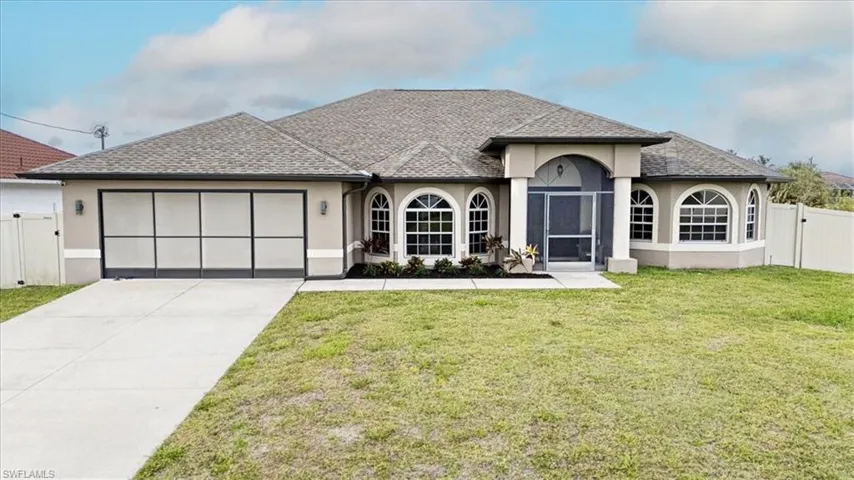 View of front facade featuring a garage, fence, a gate, and stucco siding