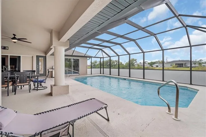Outdoor pool featuring glass enclosure, a patio area, and a ceiling fan