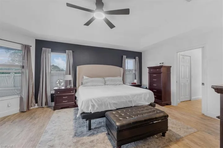 Bedroom featuring ceiling fan, light wood-style flooring, baseboards, and multiple windows