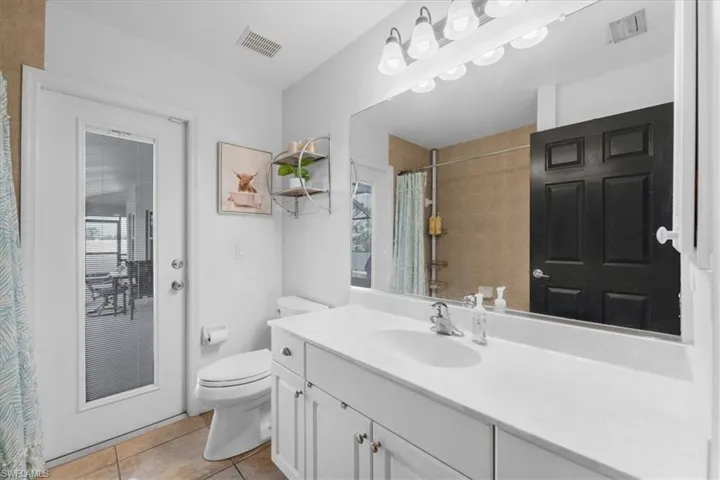 Bathroom with toilet, tile patterned flooring, curtained shower, and visible vents