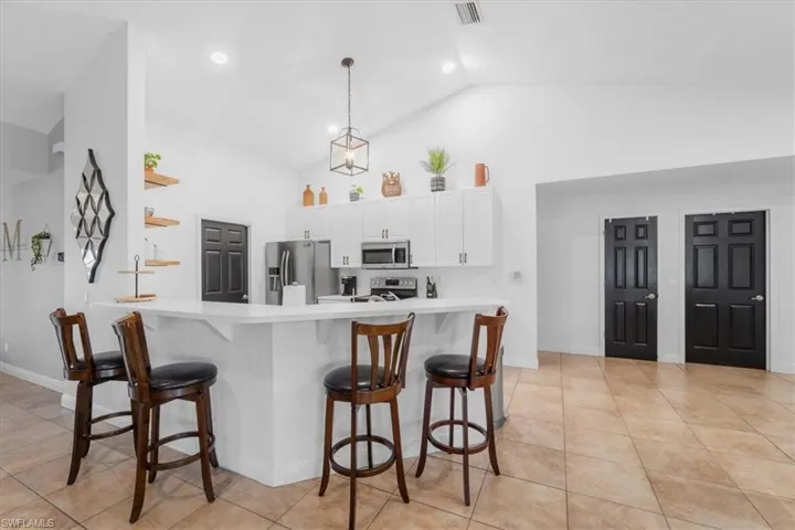 Kitchen featuring visible vents, white cabinetry, a breakfast bar area, and stainless steel appliances