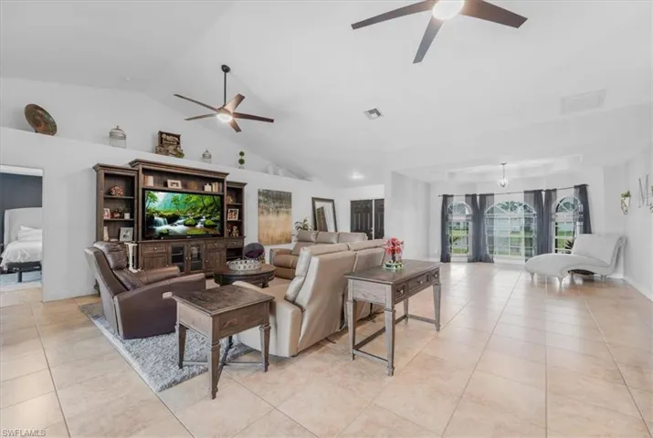 Living room featuring vaulted ceiling, visible vents, ceiling fan, and light tile patterned floors