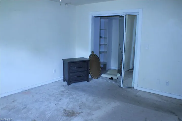Bedroom featuring concrete flooring and a closet