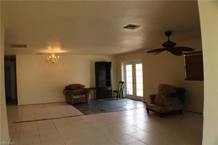 Unfurnished room featuring ceiling fan with notable chandelier, french doors, and light tile patterned floors