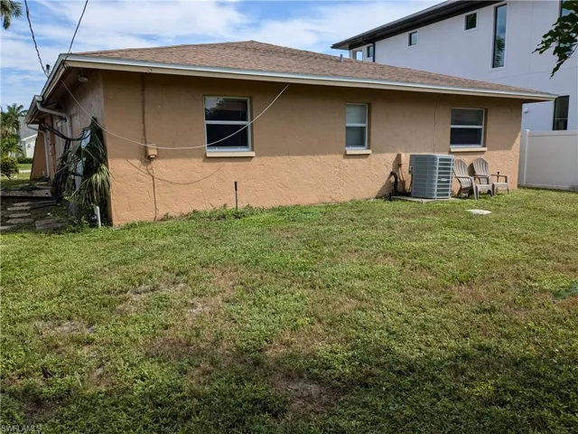 Rear view of property featuring cooling unit and a yard