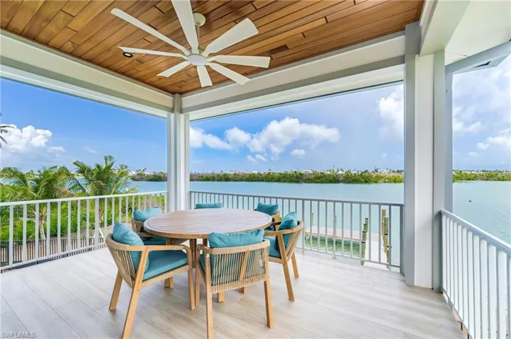 Wooden deck with a patio area, a ceiling fan, outdoor dining area, and a water view