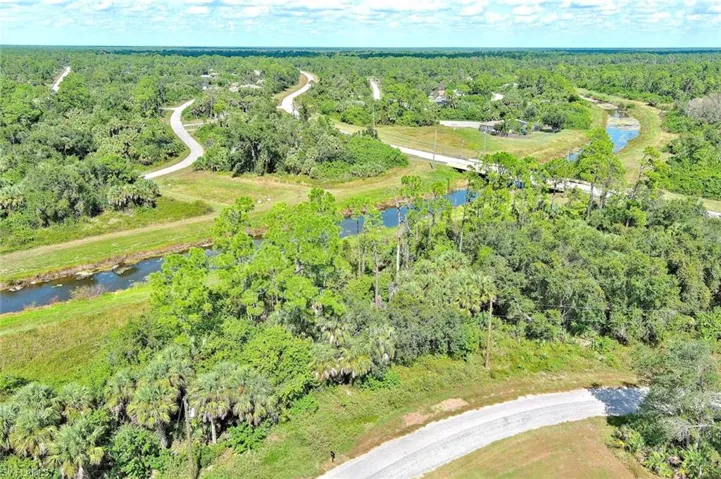 Aerial view of property and surrounding area featuring a forest and a nearby body of water