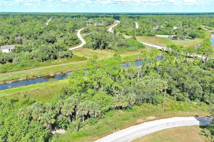 View of property location with a heavily wooded area and a nearby body of water