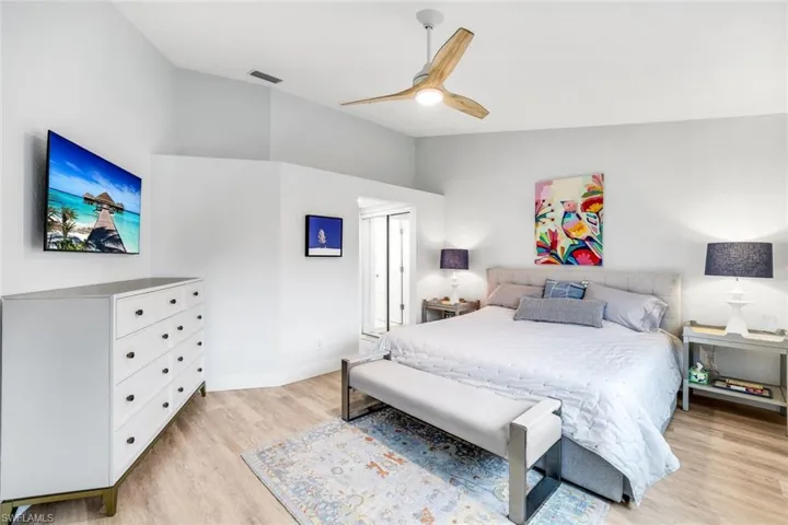 Bedroom with a closet, visible vents, light wood-style flooring, a ceiling fan, and vaulted ceiling