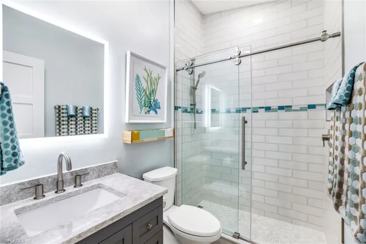 Bathroom with toilet, a stall shower, and vanity