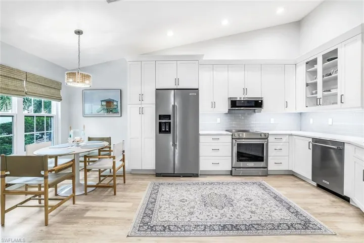Kitchen with light countertops, premium appliances, glass insert cabinets, and white cabinets