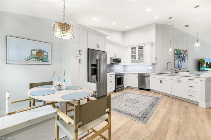 Kitchen featuring appliances with stainless steel finishes, pendant lighting, light countertops, and white cabinetry