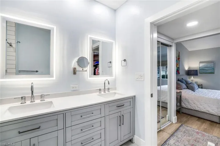 Ensuite bathroom with a sink, double vanity, connected bathroom, and wood finished floors