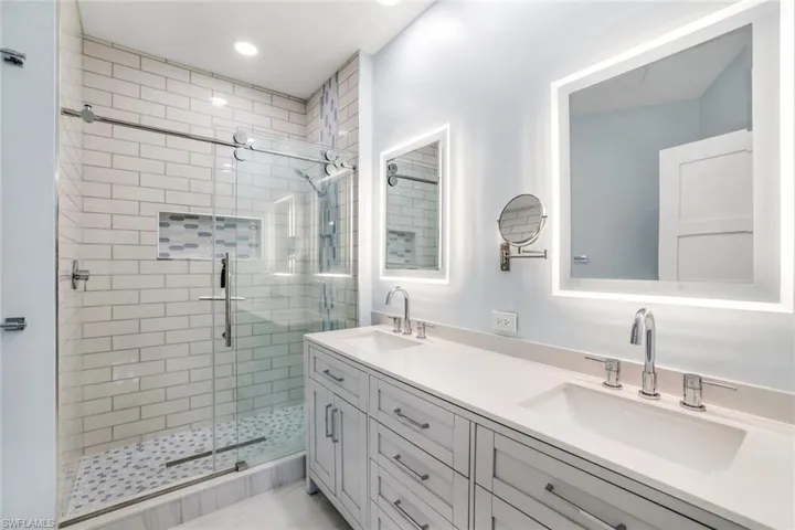 Bathroom featuring double vanity, a shower stall, a sink, and recessed lighting