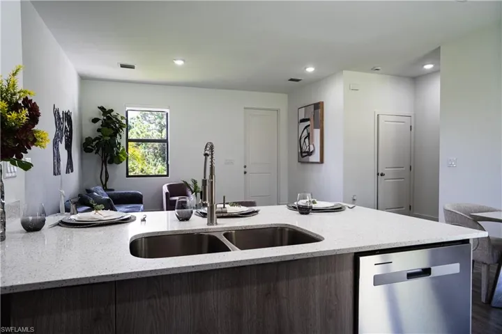 Kitchen featuring dishwasher, light stone countertops, open floor plan, a peninsula, and recessed lighting