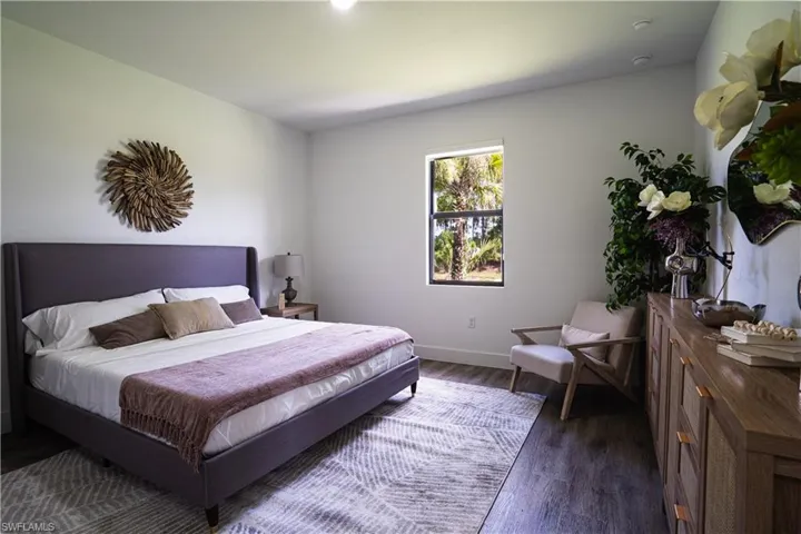 Bedroom with dark wood finished floors and baseboards