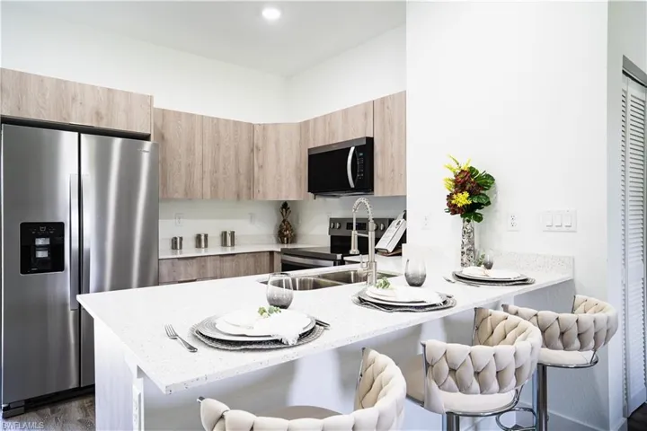 Kitchen with stainless steel appliances, light stone countertops, and a peninsula